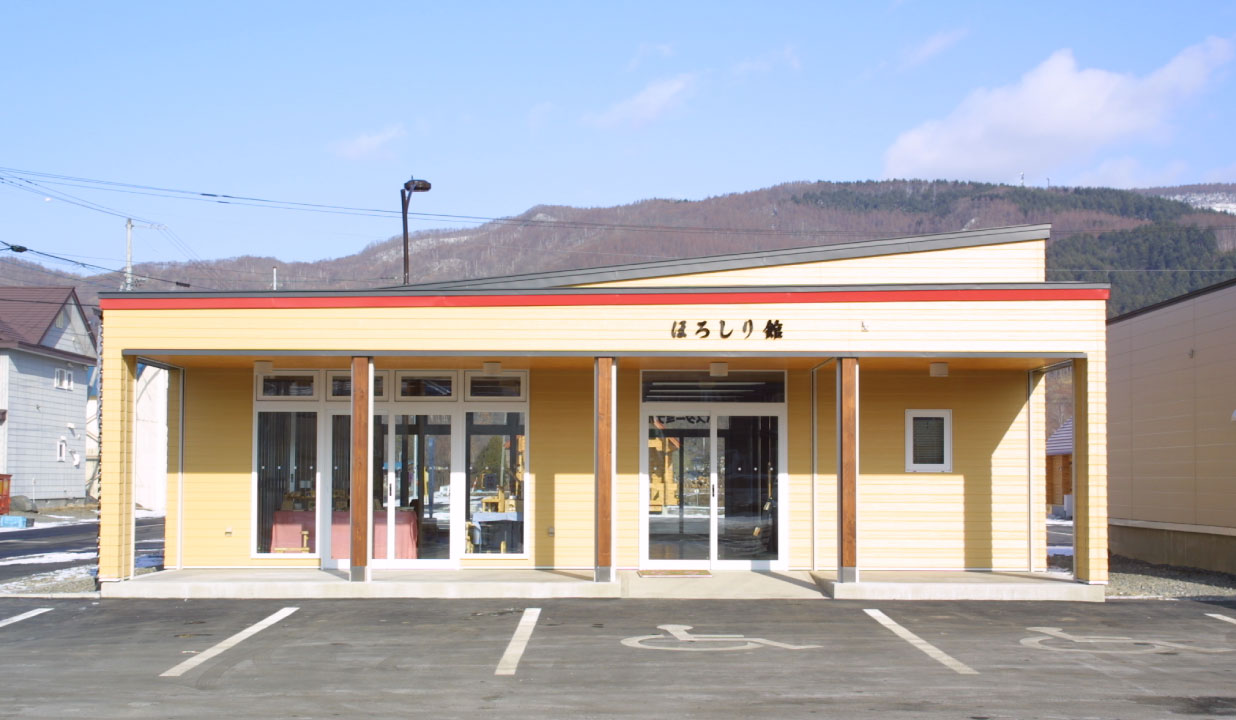 「ほろしり館」と書かれた薄い黄色を基調とした外観の山の駅ほろしり館を正面から撮った写真