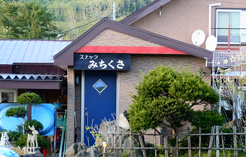 スナックみちくさと書かれた紺色の看板が設置されたレンガ調の外壁の建物の写真
