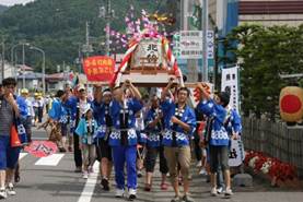 複数の子どもたちが神輿を担ぎ歩く義経神社例大祭での様子の写真