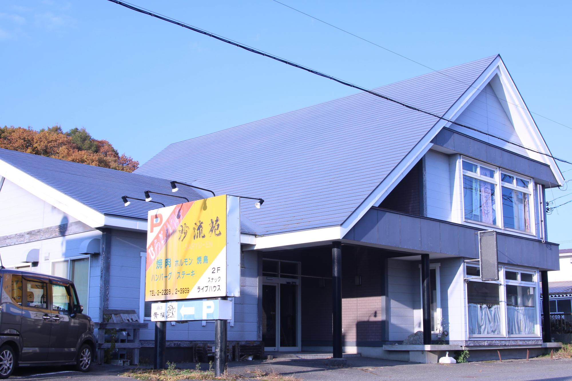 道沿いにある沙流苑と書かれた看板と建物の外観写真