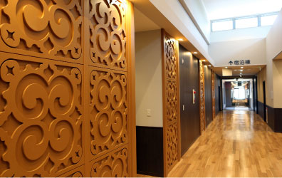 長い廊下の横にアイヌ文様が装飾された扉がいくつもあり、頭上からは日差しが差し込んでいる施設内の写真