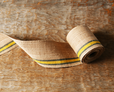 樹皮の繊維で作られた糸を使った、肌色に近い帯に緑と黄色のラインが入った「アットゥ織帯」の写真